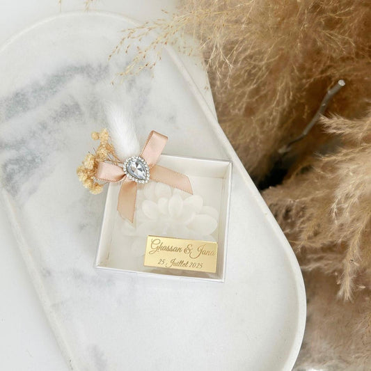 Bougie cadeau invité Diamant en coffret blanc, avec ruban beige, fleurs séchées et personnalisation sur plaque dorée.