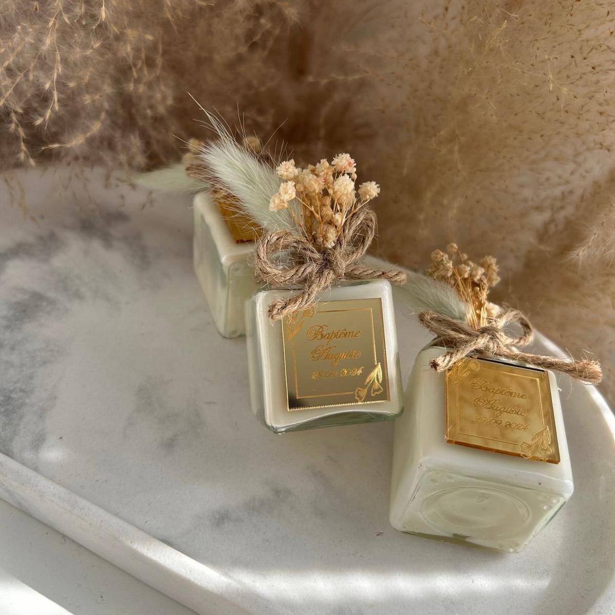 Cadeau invité baptême : bougie blanche style bohème avec jute et fleurs séchées, personnalisée avec prénom et date.