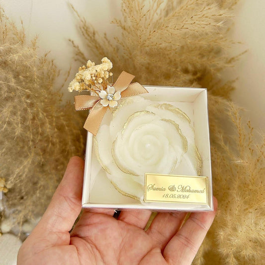 Cadeau invité mariage : bougie en forme de rose avec finitions dorées, fleurs séchées et étiquette personnalisée.