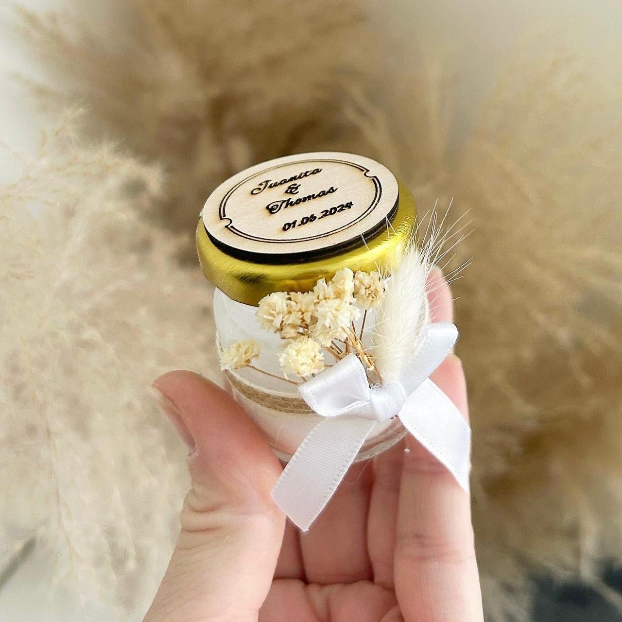 Bougie rustique personnalisée dans un petit pot en verre, couvercle doré, ruban blanc, fleurs séchées et plume, cadeau invité mariage.
