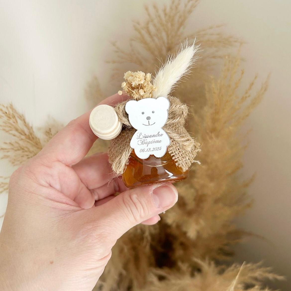 Cadeau invité baptême : petit pot de miel personnalisé avec ourson miroir, jute naturelle, fleurs séchées et cuillère en bois.