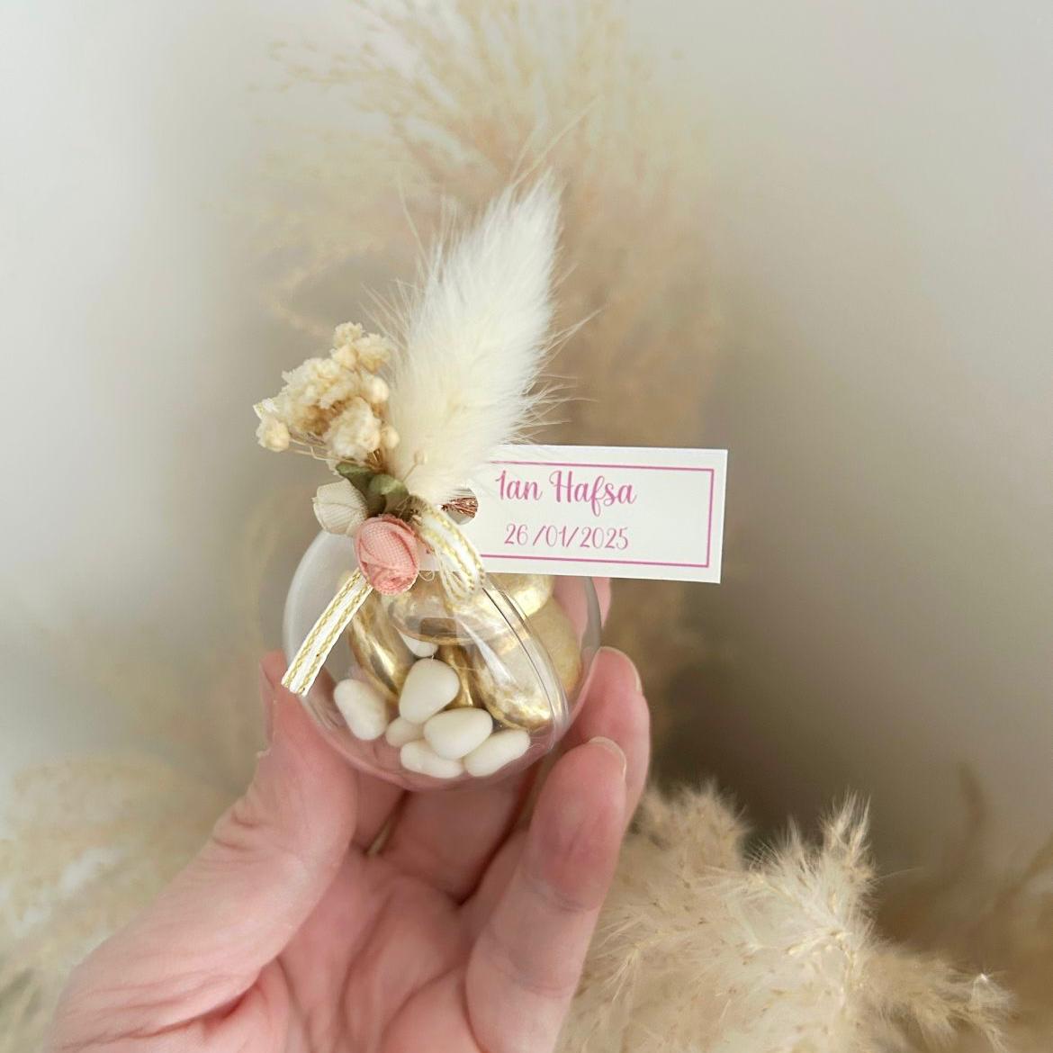 Cadeau invité : boule de dragées Vintage en plexi avec décoration bohème (plume, fleurs, rubans) et personnalisation.