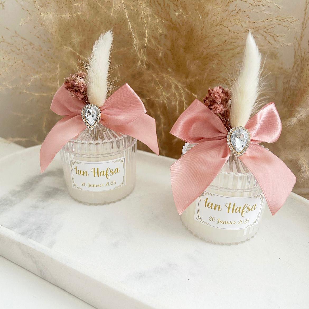 Bougie cadeau invité Queen avec nœud rose, plume blanche et strass, personnalisée avec prénoms et date.