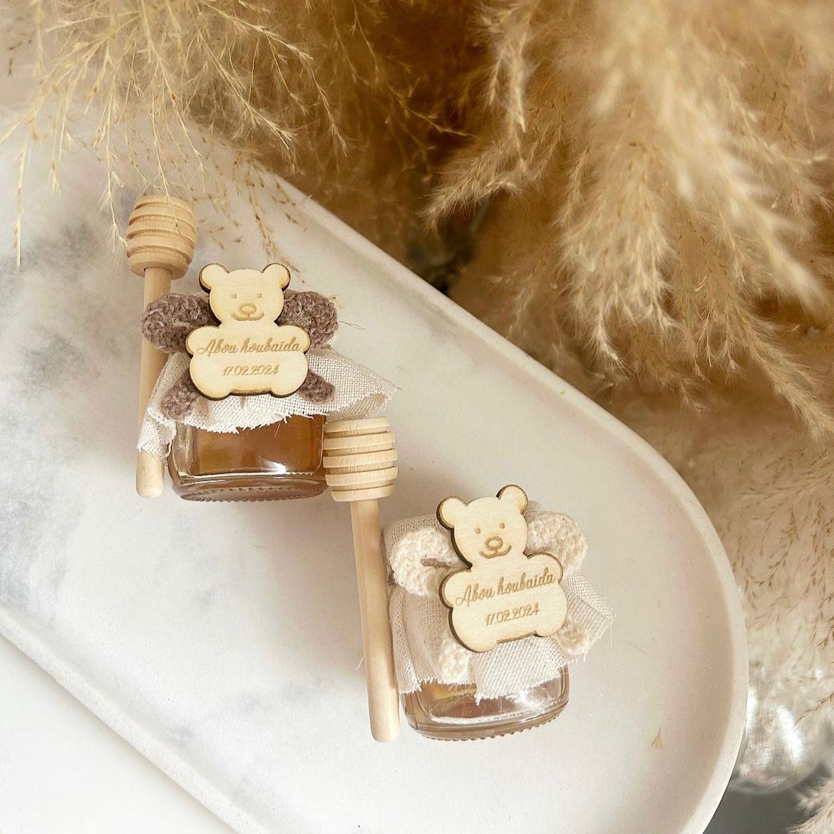 Cadeau invité baptême : petit pot de miel Teddy avec ourson en bois gravé, ruban en tissu et bâtonnet à miel.