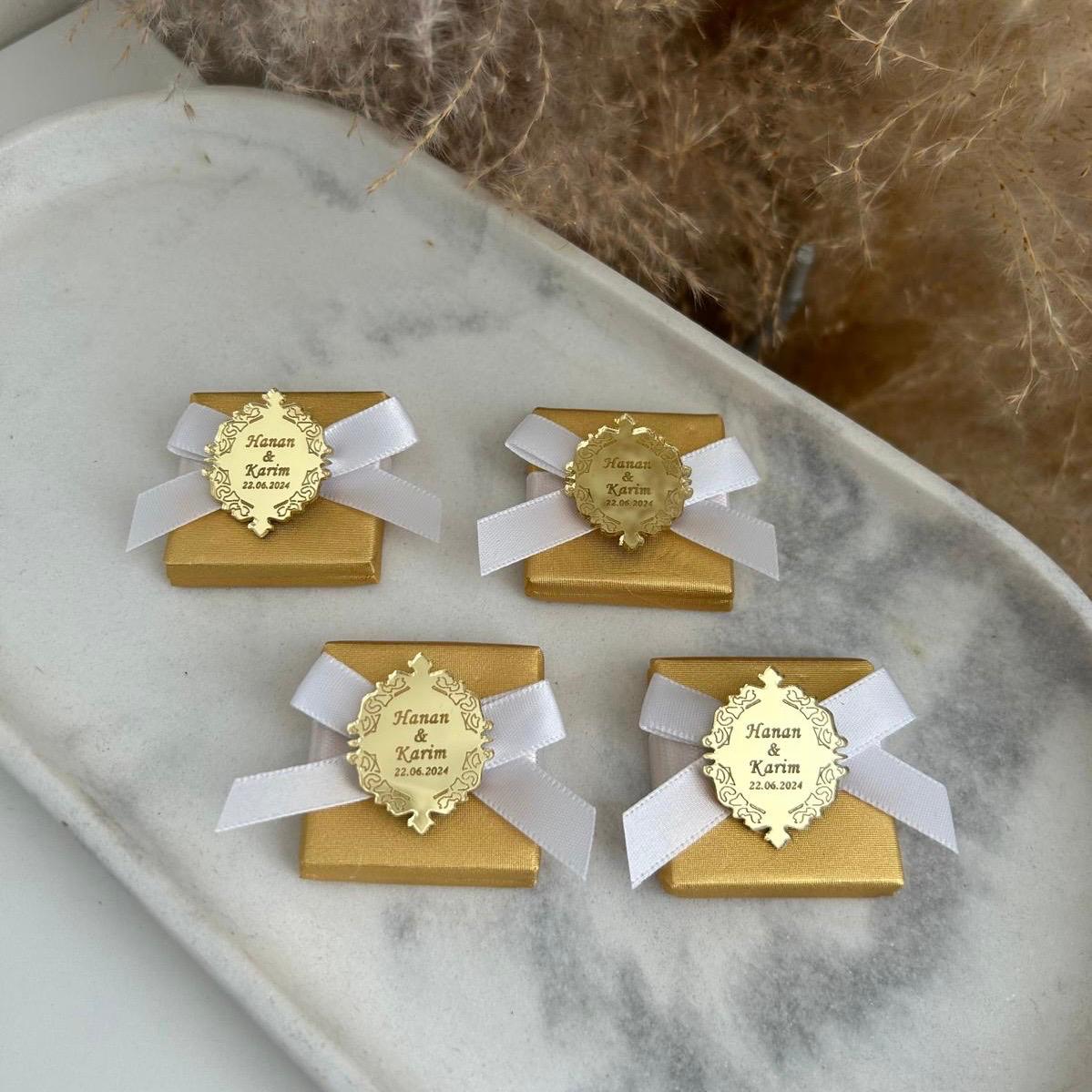 Boîte cadeau invité pour mariage, coloris or avec ruban blanc, personnalisée avec prénoms et date sur une médaille miroir