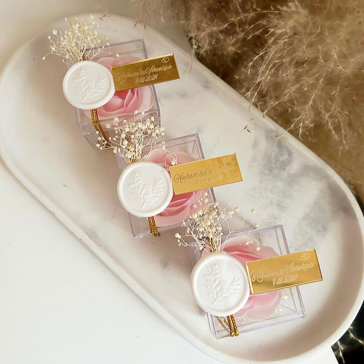 Cadeau invité : rose de savon Soélia rose en boîte plexi avec sceau blanc, fleurs séchées et plaque dorée personnalisée.